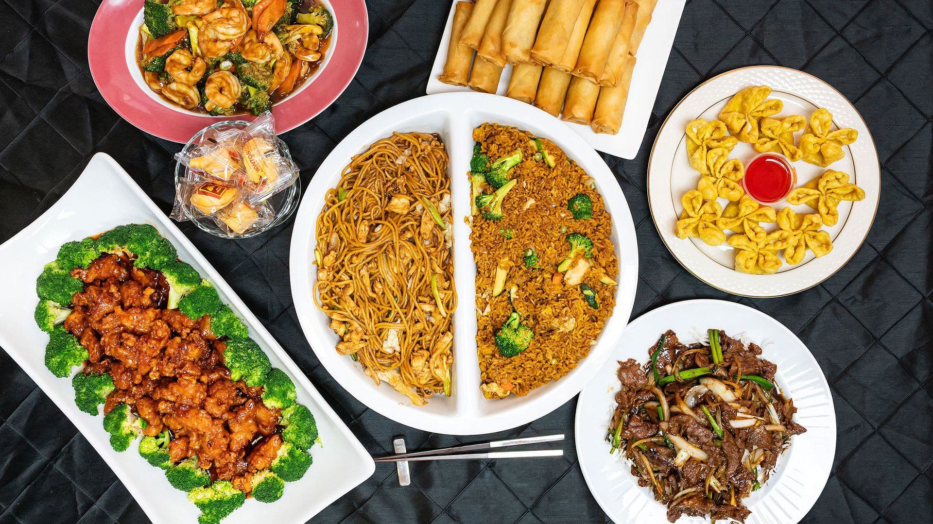 Asian food catering spread with orange chicken, lo mein and fried rice, spring rolls, crab rangoons and beef dishes